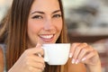 Woman tasting a coffee from a cup in a restaurant terrace