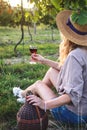 Young farmer drinking homemade red wine in vineyard