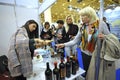 Woman tasting wine at a wine shop, seller standing at a counter