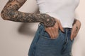 Woman with tattoos on arms against light background