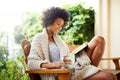 Woman, tea and reading book in garden and backyard patio feeling relax and happy. Happiness, black female person and Royalty Free Stock Photo