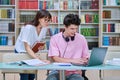 Woman mentor teaching male student in college library, exam preparation Royalty Free Stock Photo