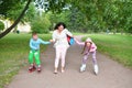 Woman teaches laughing children to roller skate in the Park