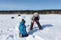 Woman teaching boy sawing snow to build an igloo, Novosibirsk, Russia