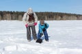 Woman teaching a boy to dig a snow block to build an igloo, Novosibirsk, Russia