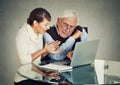 Woman teaching confused elderly man how to use laptop Royalty Free Stock Photo