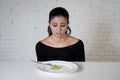 Woman or teen with fork eating dish with ridiculous little lettuce as her food symbol of crazy diet Royalty Free Stock Photo