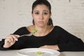 Woman or teen with fork eating dish with ridiculous little lettuce as her food symbol of crazy diet Royalty Free Stock Photo