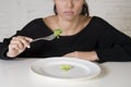 Woman or teen with fork eating dish with ridiculous little lettuce as her food symbol of crazy diet Royalty Free Stock Photo