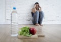 Woman or teenager girl sitting on ground alone worried at home suffering nutrition eating disorder