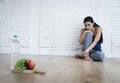 Woman or teenager girl sitting on ground alone worried at home suffering nutrition eating disorder