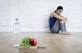 Woman or teenager girl sitting on ground alone worried at home suffering nutrition eating disorder Royalty Free Stock Photo