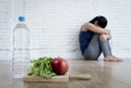 Woman or teenager girl sitting on ground alone worried at home suffering nutrition eating disorder