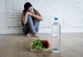 Woman or teenager girl sitting on ground alone worried at home suffering nutrition eating disorder