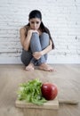 Woman or teenager girl sitting on ground alone worried at home suffering nutrition eating disorder