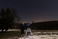 Woman with telescope under winter night sky Woman looking through telescope under starry night. Royalty Free Stock Photo