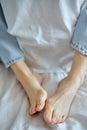 Woman tender foots. Cropped lady in denim jeans relaxing on bed in the morning, have rest