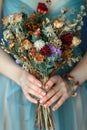 A woman tender grasp on a bouquet of dried flowers