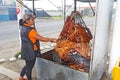 A woman tends to roasting meat at a restaurant on the side of a