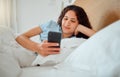 Woman texting, checking messages and holding phone while reading sms and lying awake in her bed in the morning. Happy Royalty Free Stock Photo
