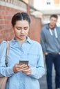 Young Woman Texting For Help On Mobile Phone Whilst Being Stalke