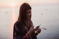 Woman texting on smart phone on the beach during sunset Royalty Free Stock Photo