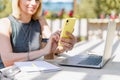 Woman texting with smartphone outside in park. Happy and smiling girl working outside, using laptop and mobile phone. Distance Royalty Free Stock Photo