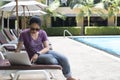 Woman texting and working on laptop by the pool Royalty Free Stock Photo