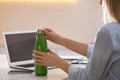 Woman with thermo bottle working at table in modern office, closeup