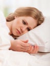 Woman with thermometer sick colds, flu, fever in bed