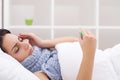 Woman with thermometer sick colds, flu, fever, headache in bed