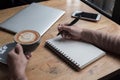 A woman is thinking business concept at the office. she holding a cup off coffee. on the table have laptop and smartphone.