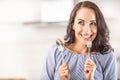 Woman thinking of eating something good bites into a fork while holding spoon in the other hand