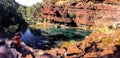 A woman thinking and other tourists relaxing on the rocks of the Fortescue Falls in Karijini, WA