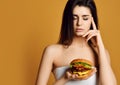 Woman thinking to eat double cheeseburger beef sandwich with hungry mouth. Diet and Fast food concept