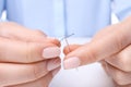 Woman threading sewing needle at table, closeup