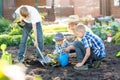 Woman with three children sons planting a tree and watering it together in garden Royalty Free Stock Photo