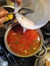 Woman throw sour cream to saucepan with borscht