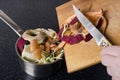 Woman throwing away leftover vegetables peelings.Concept of composting.Pot full of peelings, woman holding knife and wooden cuttin