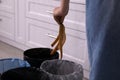 Woman throwing banana peel into trash bin in kitchen, closeup. Separate waste collection