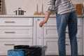 Woman throwing plastic bottle into trash bin in kitchen, closeup. Separate waste collection