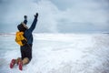 Woman throwing snow while kneeling on frozen wave