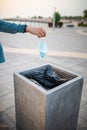 Woman throwing a used surgical face mask in the trash outdoors Royalty Free Stock Photo