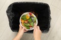 Woman throwing vegetable salad into bin indoors, top view Royalty Free Stock Photo