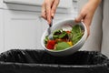 Woman throwing vegetable salad into bin indoors, closeup Royalty Free Stock Photo