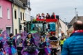 A woman throws candy to the crowd from a parade float and a group of costumed women goes ahead at the carnival parade