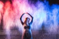 Woman throws color powder on dark background