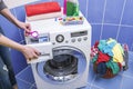 Woman throws laundry detergent into the washing machine. Royalty Free Stock Photo