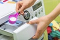 Woman throws laundry detergent into the washing machine.