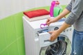 Woman throws laundry detergent into the washing machine. Royalty Free Stock Photo